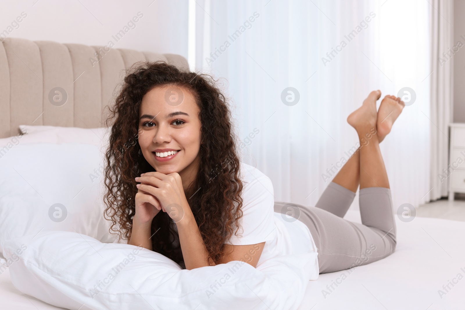 Photo of Happy African American woman lying on bed at home