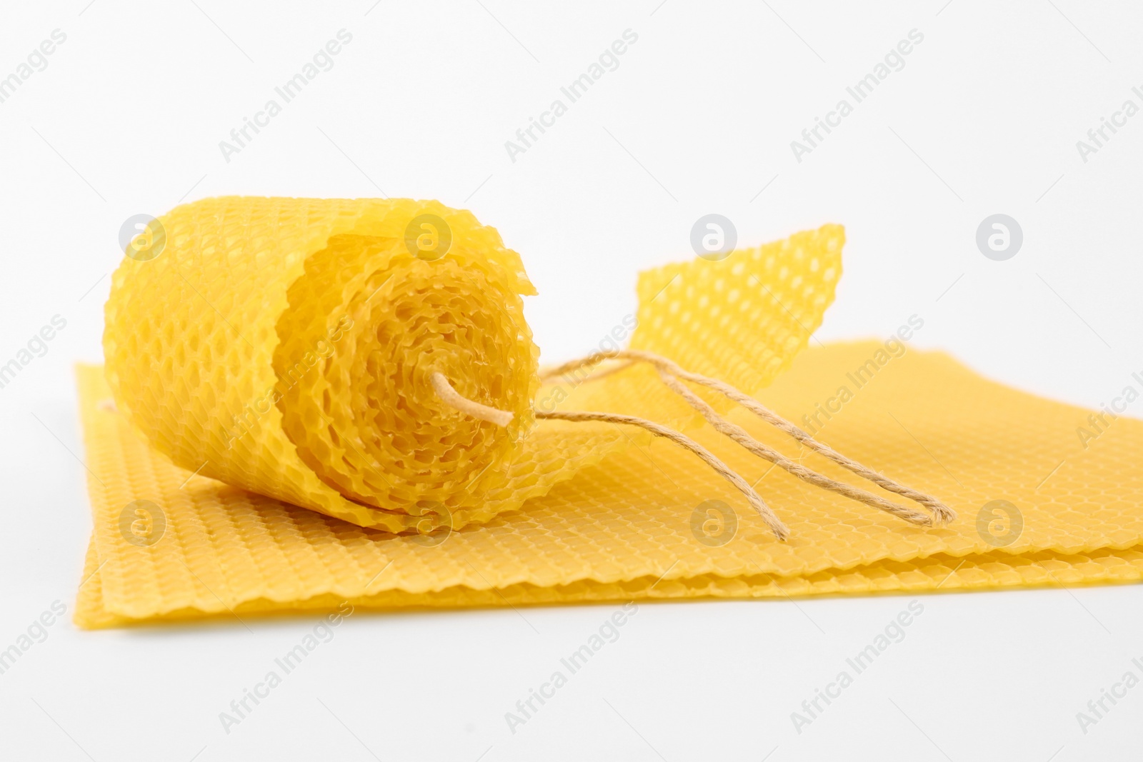 Photo of Stylish elegant beeswax candle and wax sheets on white background