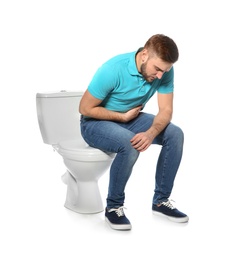 Photo of Young man suffering from digestive disorder on toilet bowl, white background