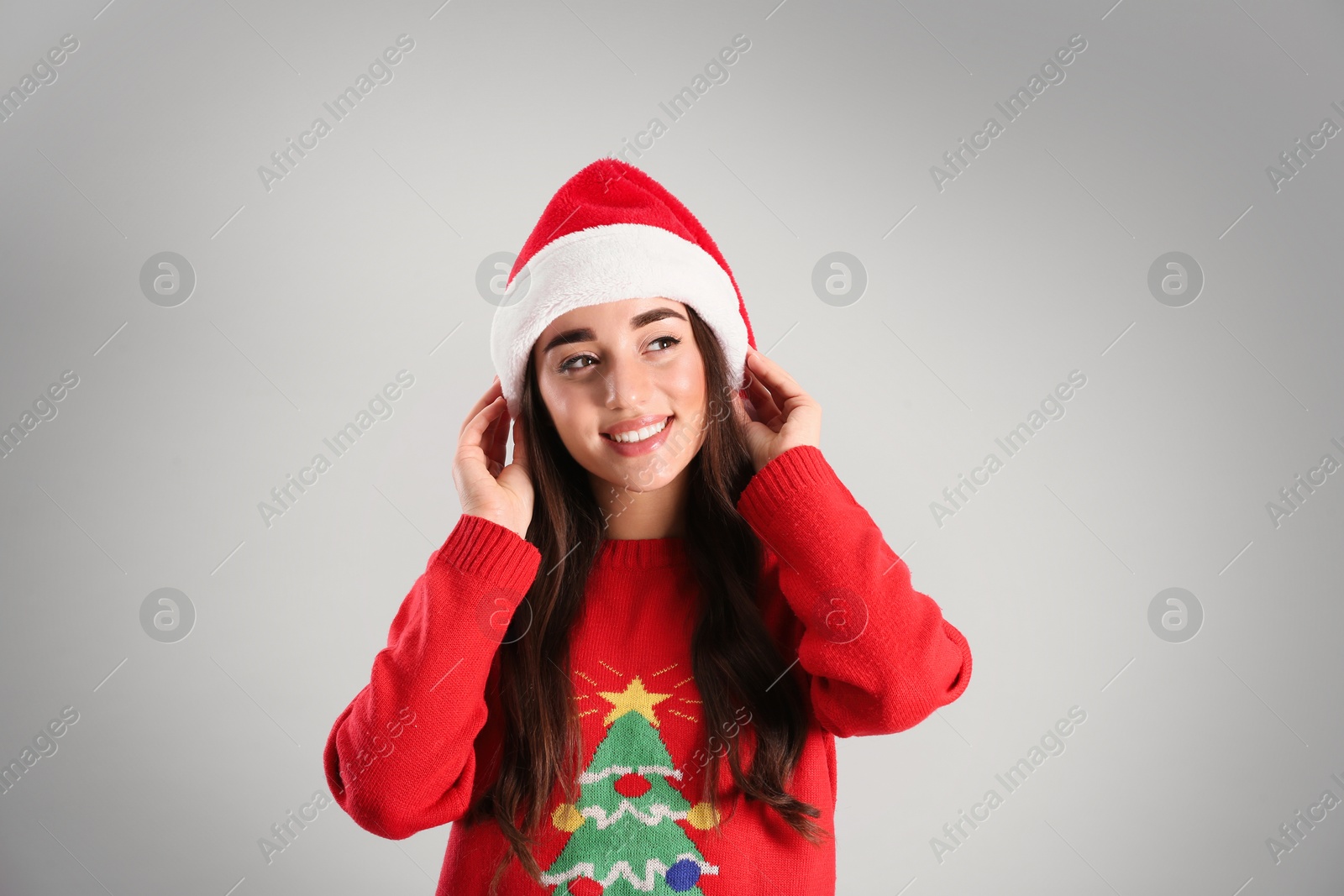 Photo of Beautiful woman wearing Santa Claus hat on light grey background