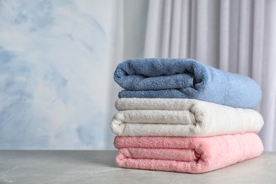 Photo of Stack of soft bath towels on table against blurred background. Space for text