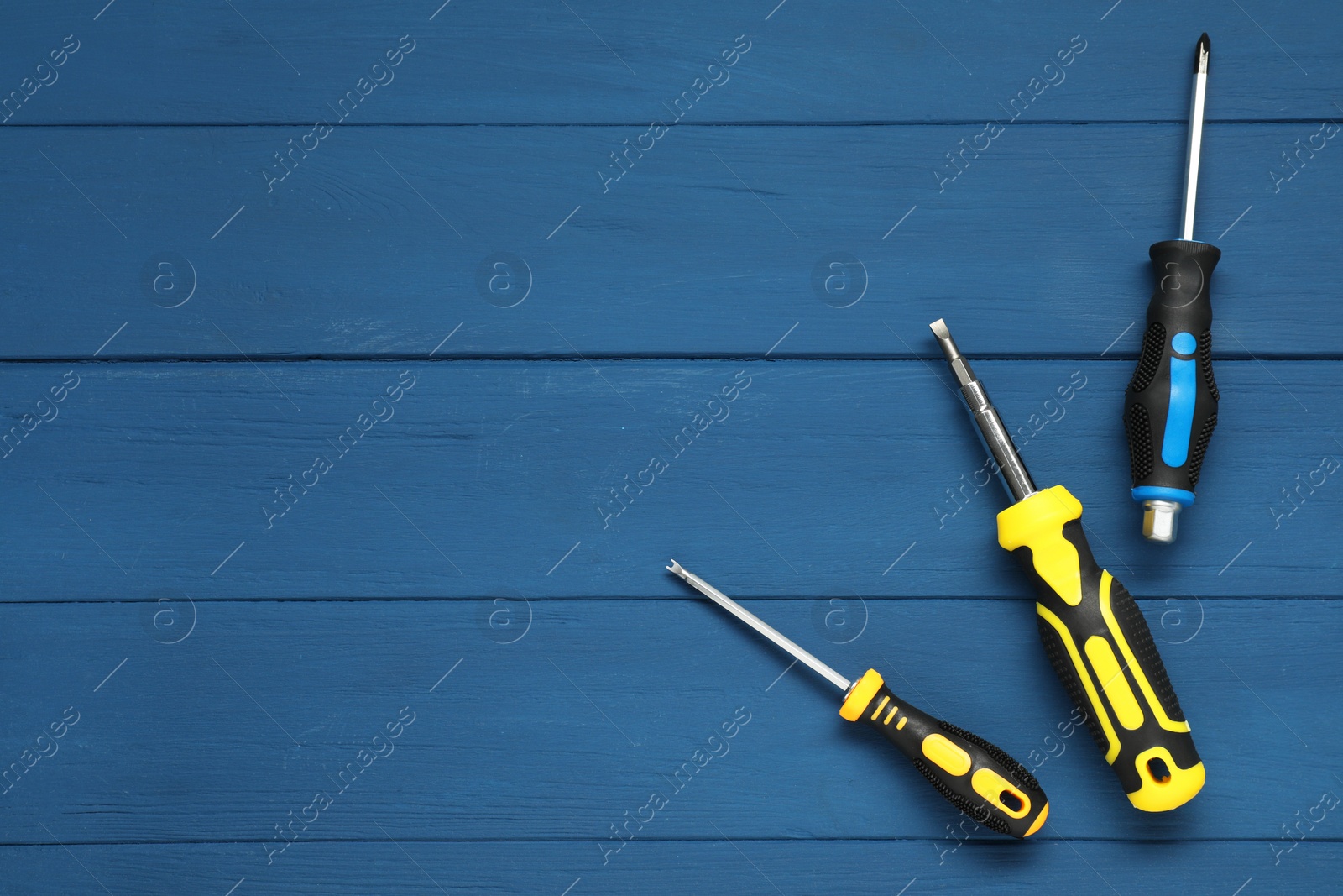 Photo of Set of screwdrivers on blue wooden table, top view. Space for text