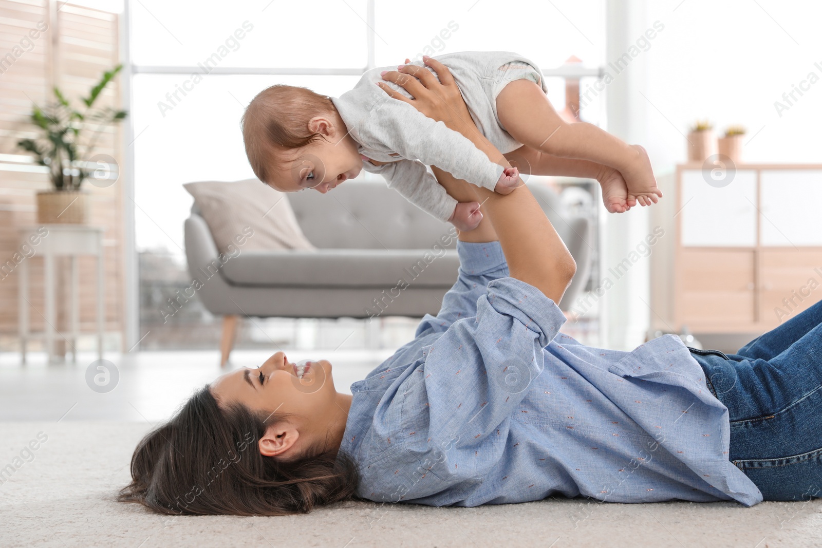 Photo of Happy young mother playing with baby on floor at home