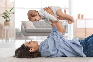 Photo of Happy young mother playing with baby on floor at home