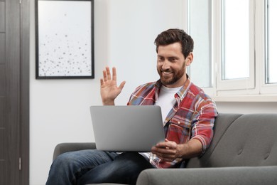 Photo of Happy bearded man having video chat on laptop at home