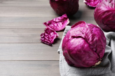 Photo of Fresh red cabbages on wooden table, space for text