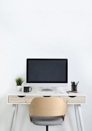 Photo of Cozy workspace with computer, houseplant and stationery on wooden desk at home