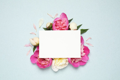 Photo of Beautiful peonies and blank card on light blue background, flat lay. Space for text