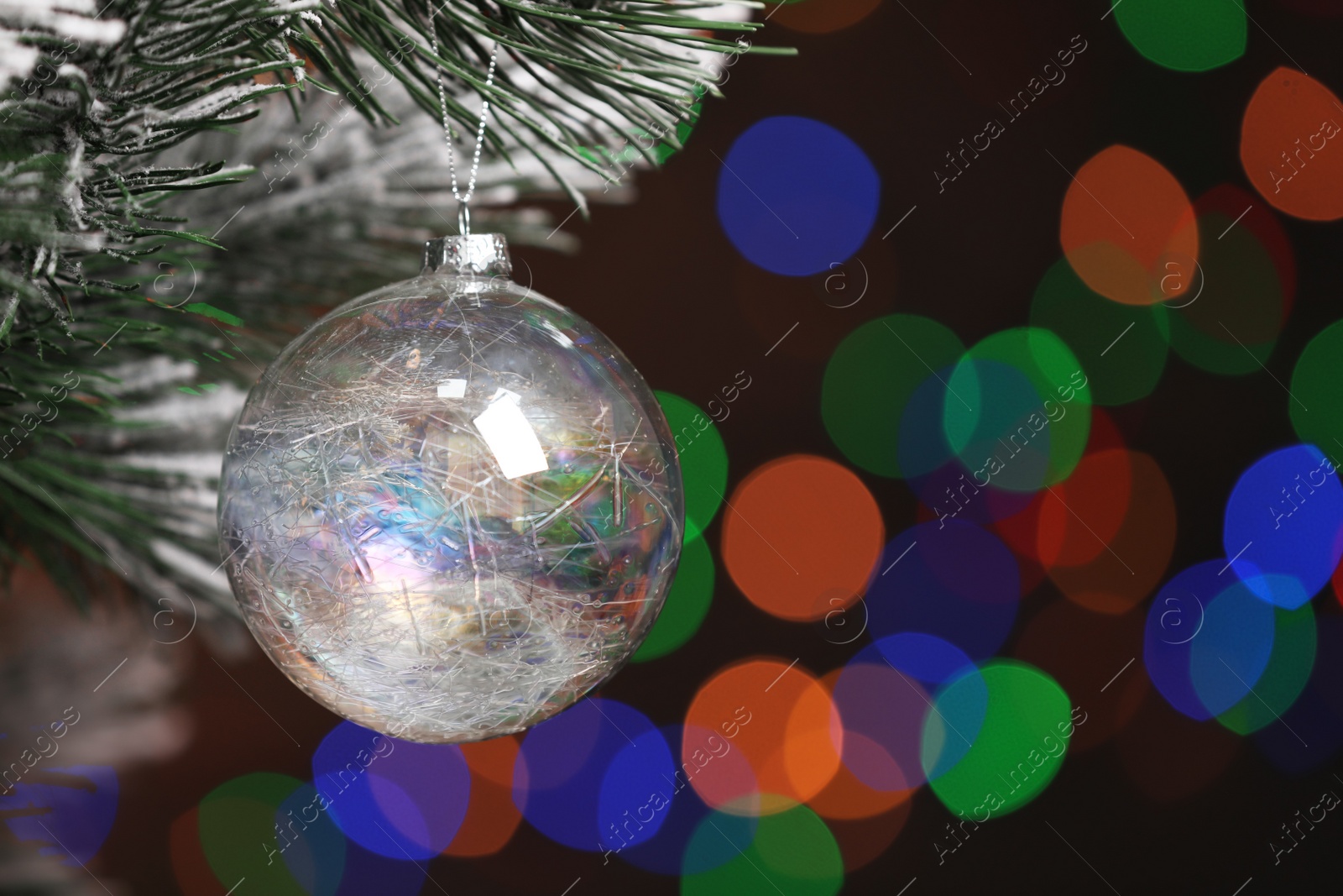 Photo of Beautiful holiday bauble hanging on Christmas tree against blurred festive lights, closeup. Space for text