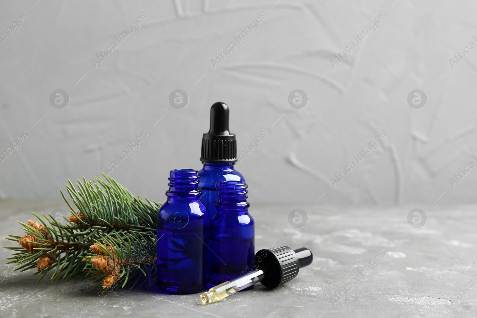 Photo of Composition with bottles of conifer essential oil on grey table. Space for text