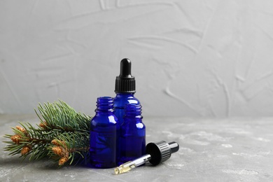 Composition with bottles of conifer essential oil on grey table. Space for text