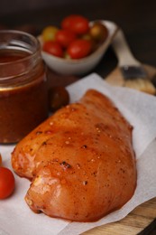 Photo of Raw marinated chicken fillets on wooden table, closeup