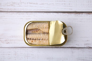 Photo of Open tin can with mackerel fillets on white wooden table, top view