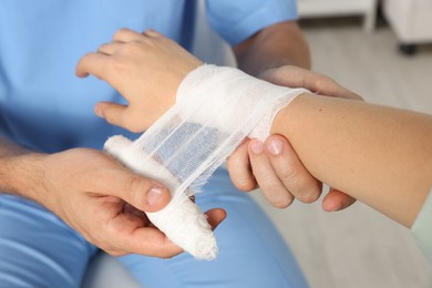 Photo of Doctor applying bandage onto patient's wrist in hospital, closeup