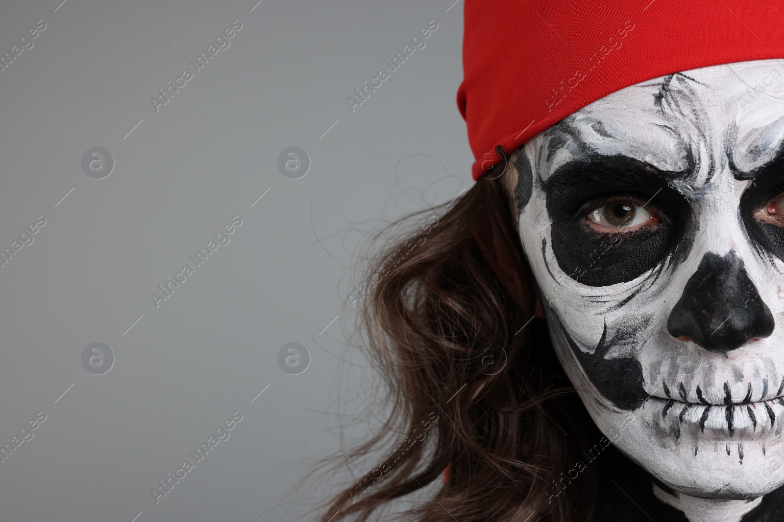 Photo of Man with skull makeup and red bandana on light grey background, closeup and space for text. Halloween celebration