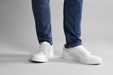 Photo of Man wearing stylish white sneakers on grey background, closeup