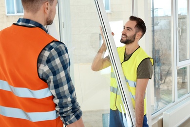 Photo of Construction workers installing plastic window in house