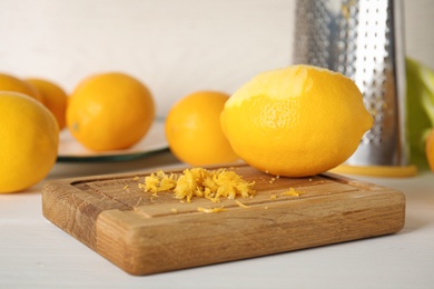 Grated lemon zest and fresh fruits on white wooden table, closeup