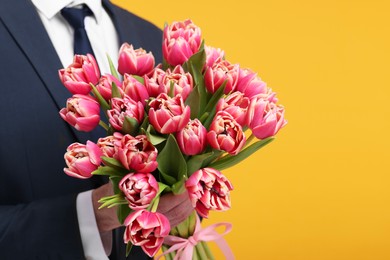 Photo of Man with beautiful bouquet on orange background, closeup