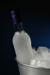 Photo of Bottle of vodka in metal bucket with ice on dark background