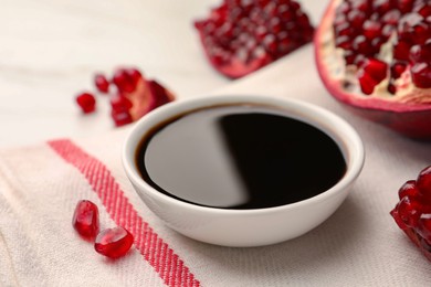 Photo of Bowl of pomegranate sauce and fresh ripe fruit on table, closeup