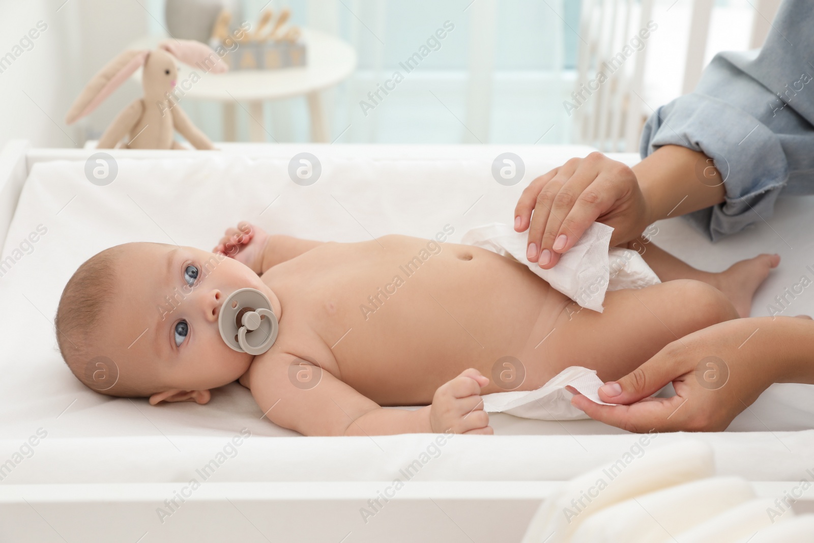 Photo of Mother changing her baby's diaper on table at home