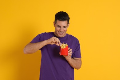 Photo of Man with French fries on orange background