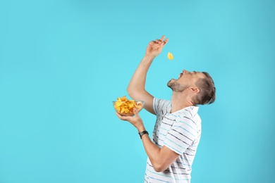 Photo of Man eating potato chips on color background. Space for text