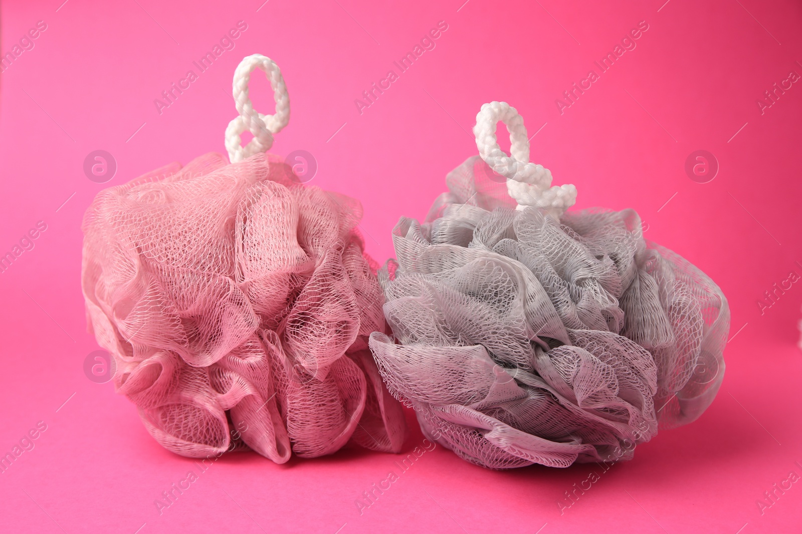 Photo of Colorful shower puffs on pink background. Personal hygiene
