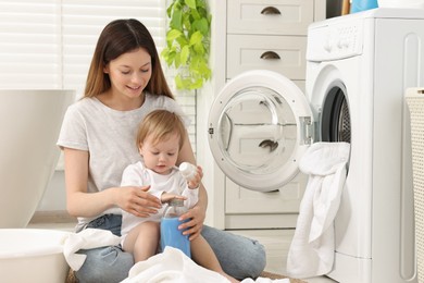 Photo of Happy mother with her daughter washing baby clothes in bathroom