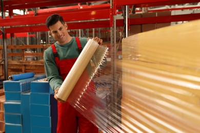 Photo of Worker wrapping boxes in stretch film at warehouse