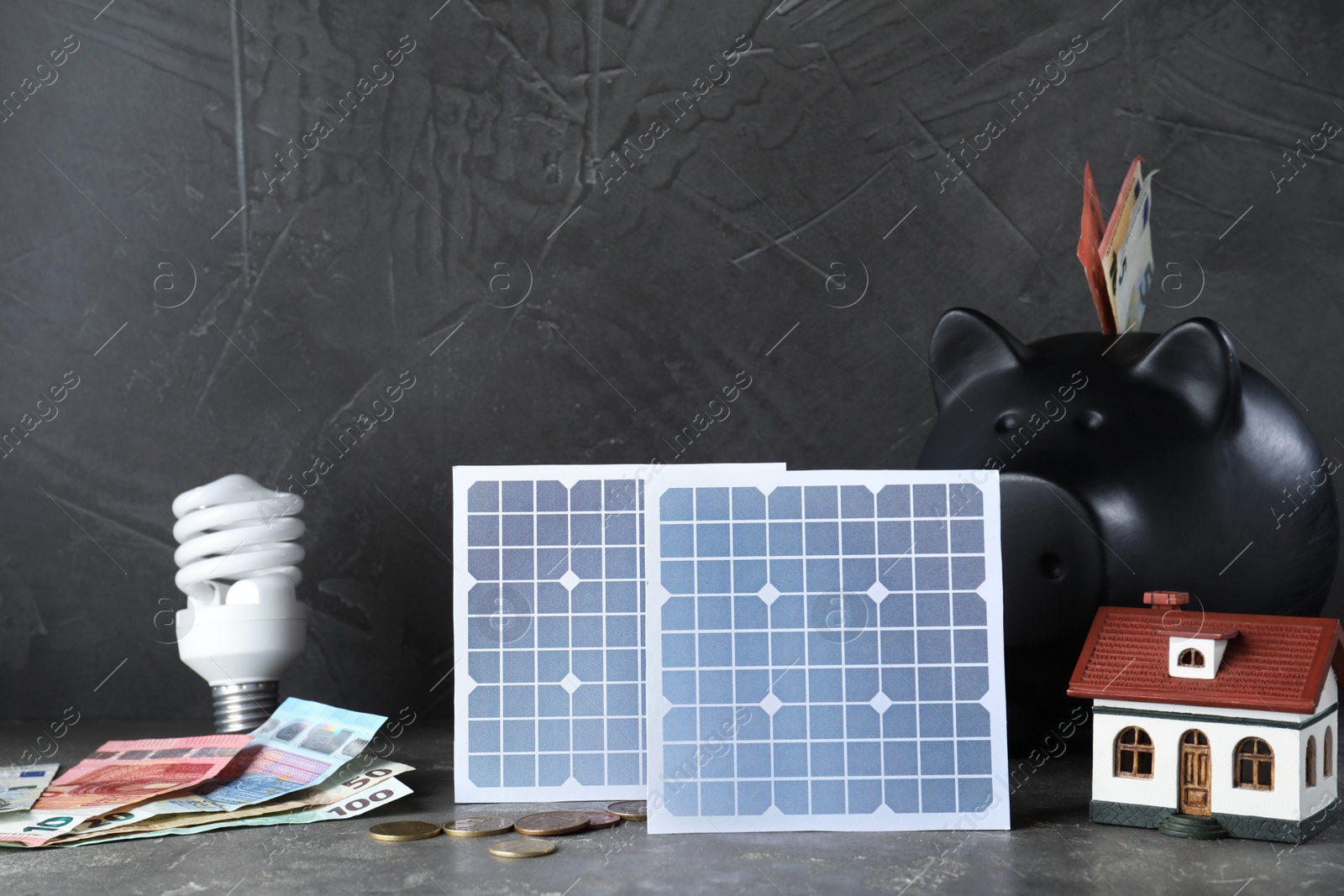 Photo of Composition with solar panels and piggy bank on grey stone table