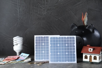 Composition with solar panels and piggy bank on grey stone table