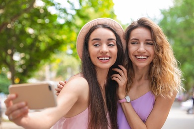 Beautiful young women taking selfie outdoors on sunny day