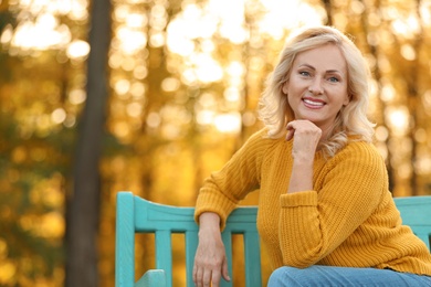 Portrait of happy mature woman on bench in park