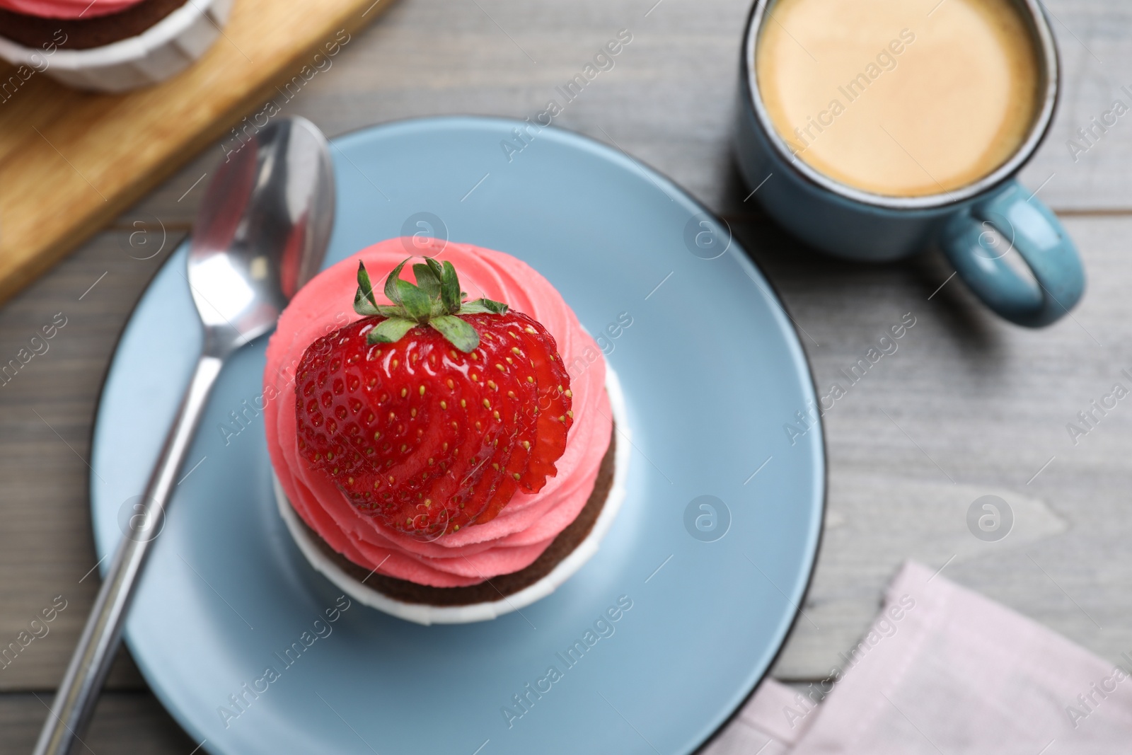 Photo of Sweet cupcake with fresh strawberry served on wooden table, flat lay