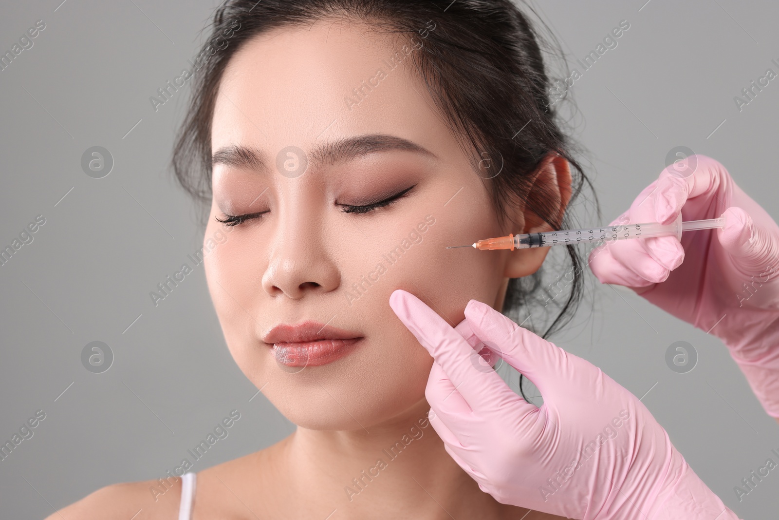 Photo of Woman getting facial injection on grey background, closeup