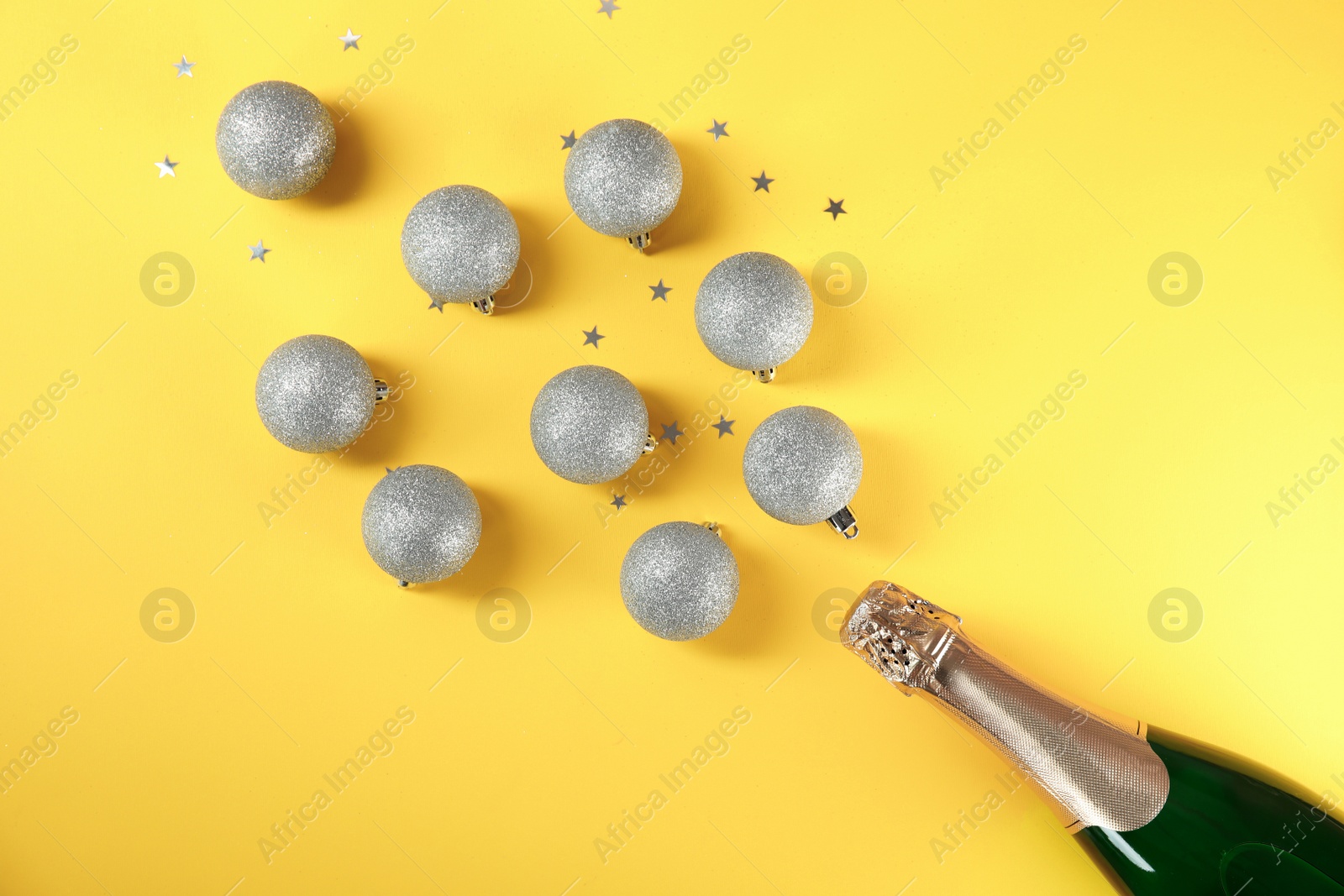 Photo of Christmas composition with bottle of champagne and balls on color background, top view