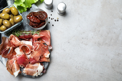 Photo of Tasty prosciutto served on light grey table, flat lay. Space for text