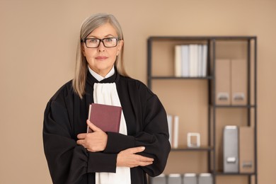 Portrait of judge in court dress with book indoors. Space for text