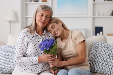 Happy mature mother and her daughter with beautiful cornflowers at home