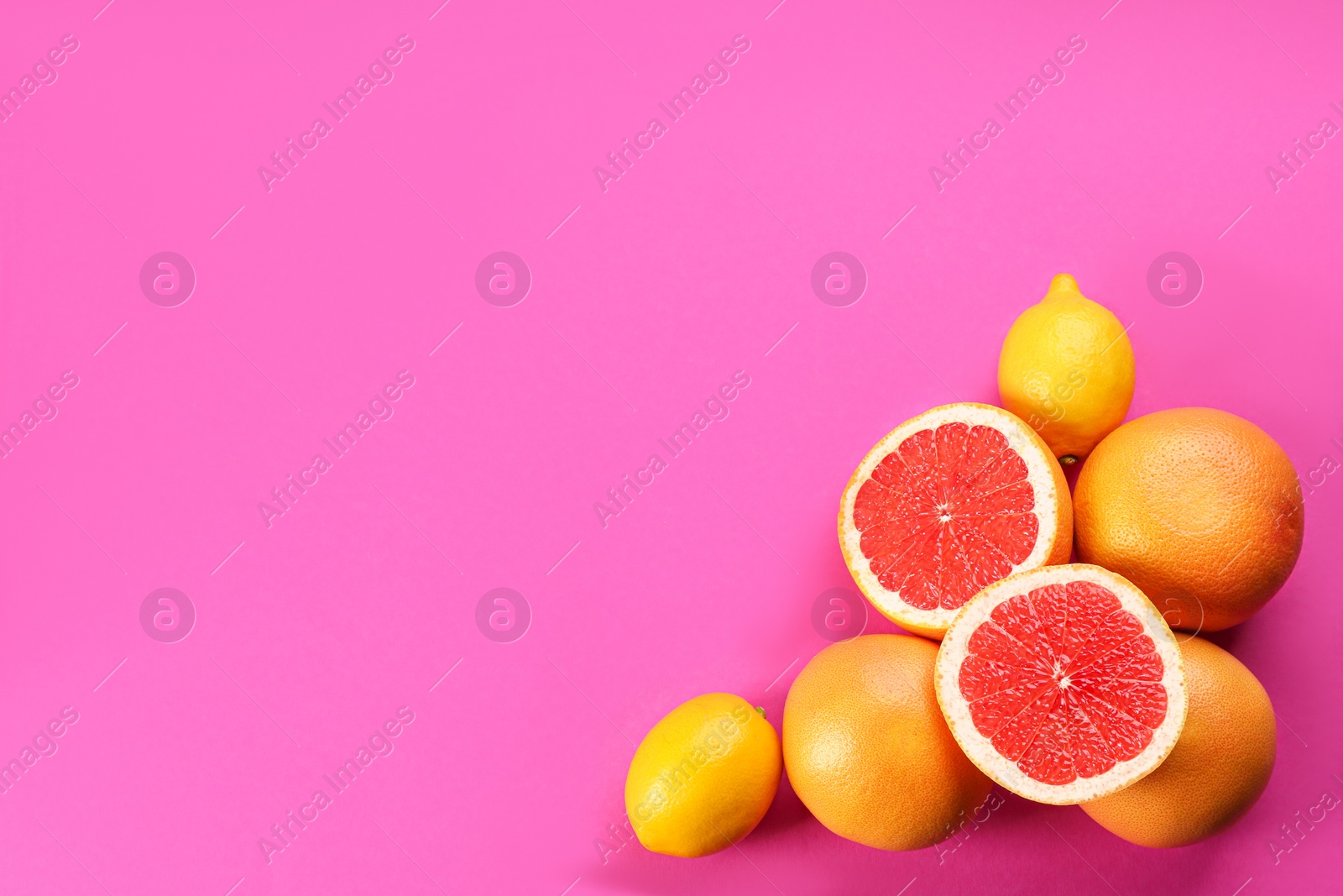 Photo of Fresh ripe grapefruits and lemons on magenta background, flat lay. Space for text