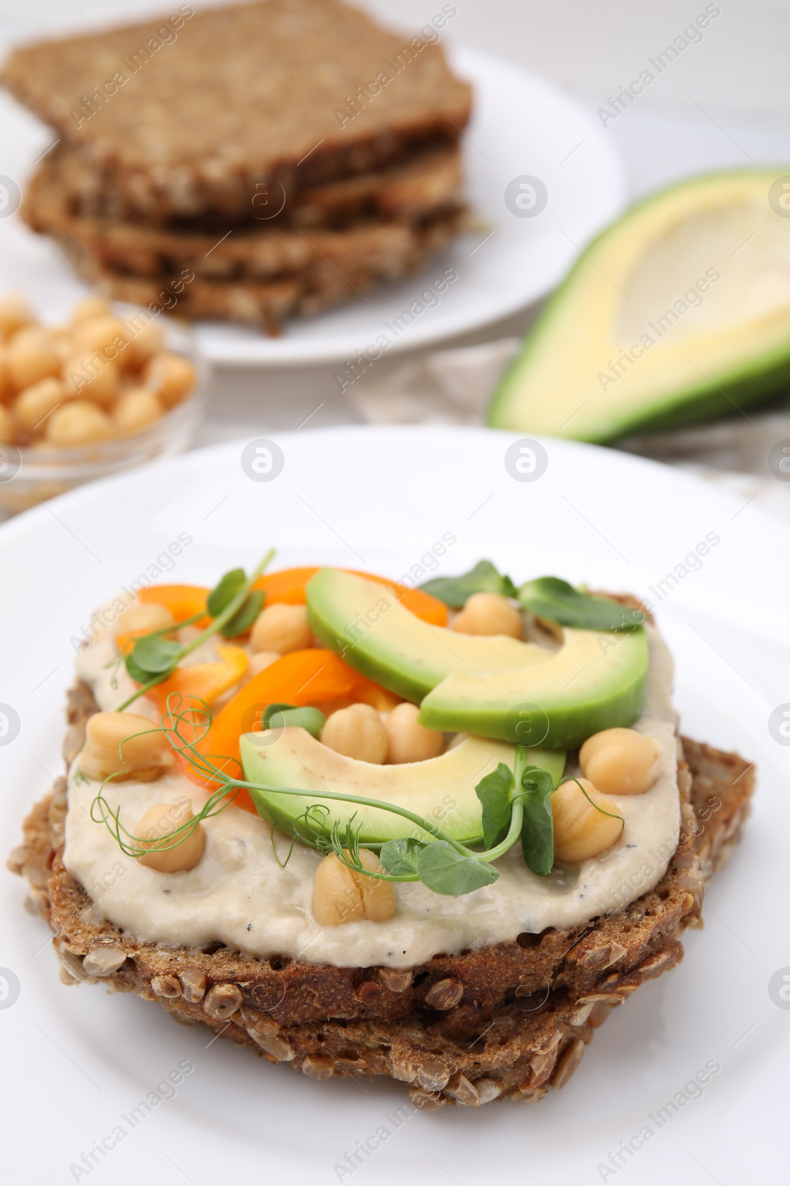 Photo of Tasty vegan sandwich with avocado, chickpeas and bell pepper on table, closeup