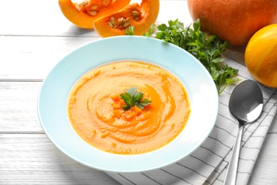 Photo of Plate with tasty pumpkin soup served on wooden table