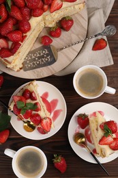 Tasty cake with fresh strawberries, mint and cups of coffee on wooden table, flat lay