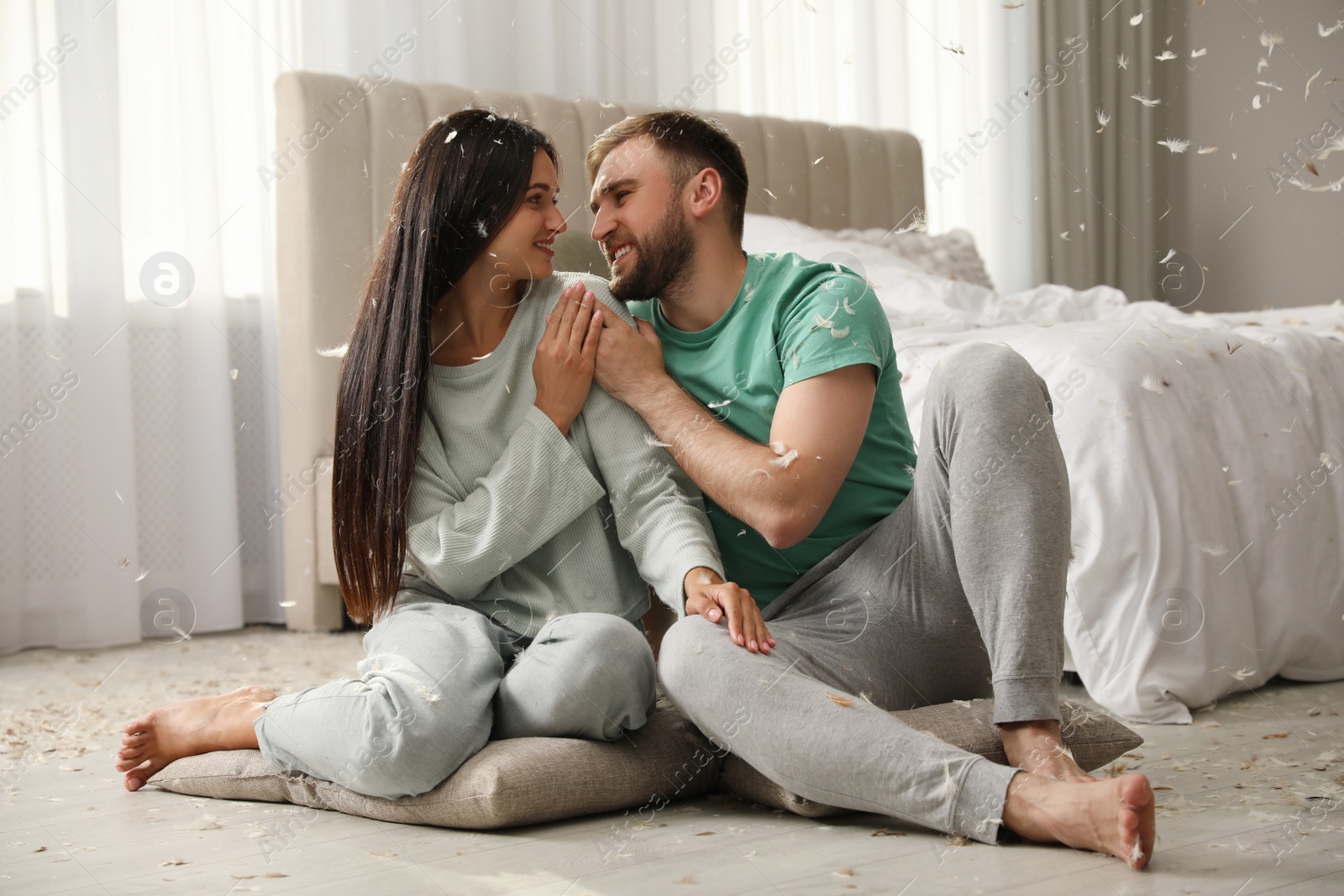 Photo of Happy young couple resting after fun pillow fight in bedroom