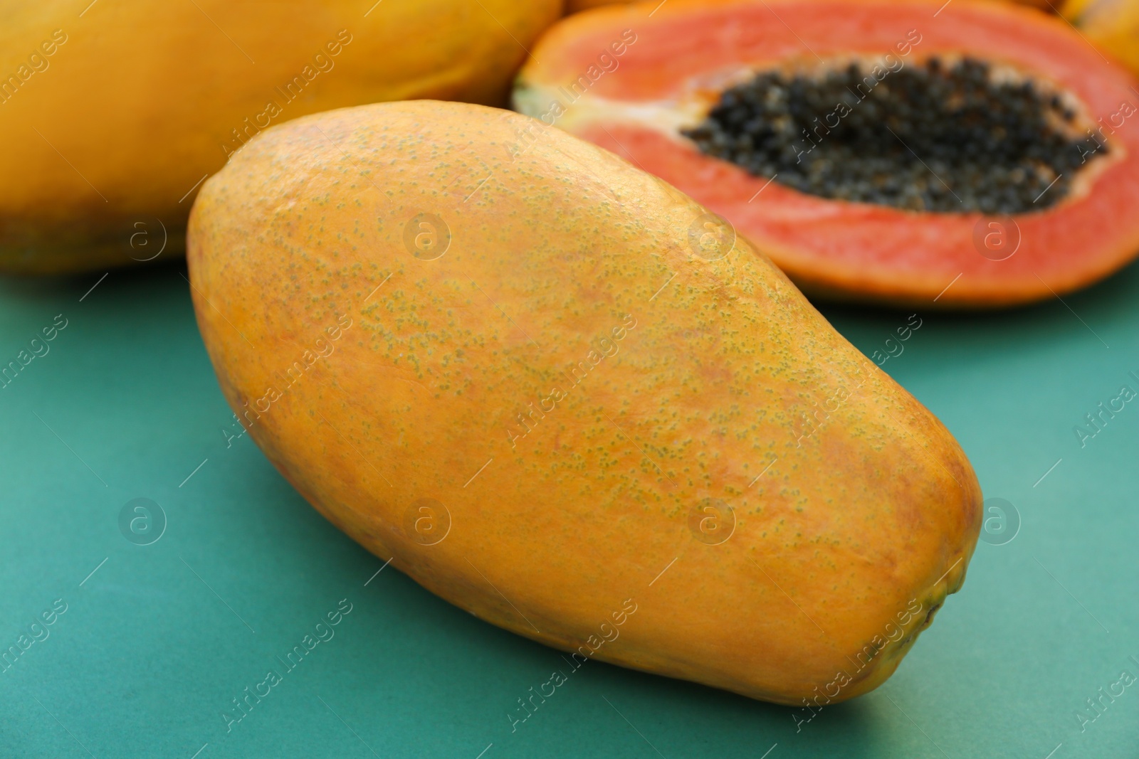 Photo of Fresh ripe cut and whole papaya fruits on light blue background, closeup