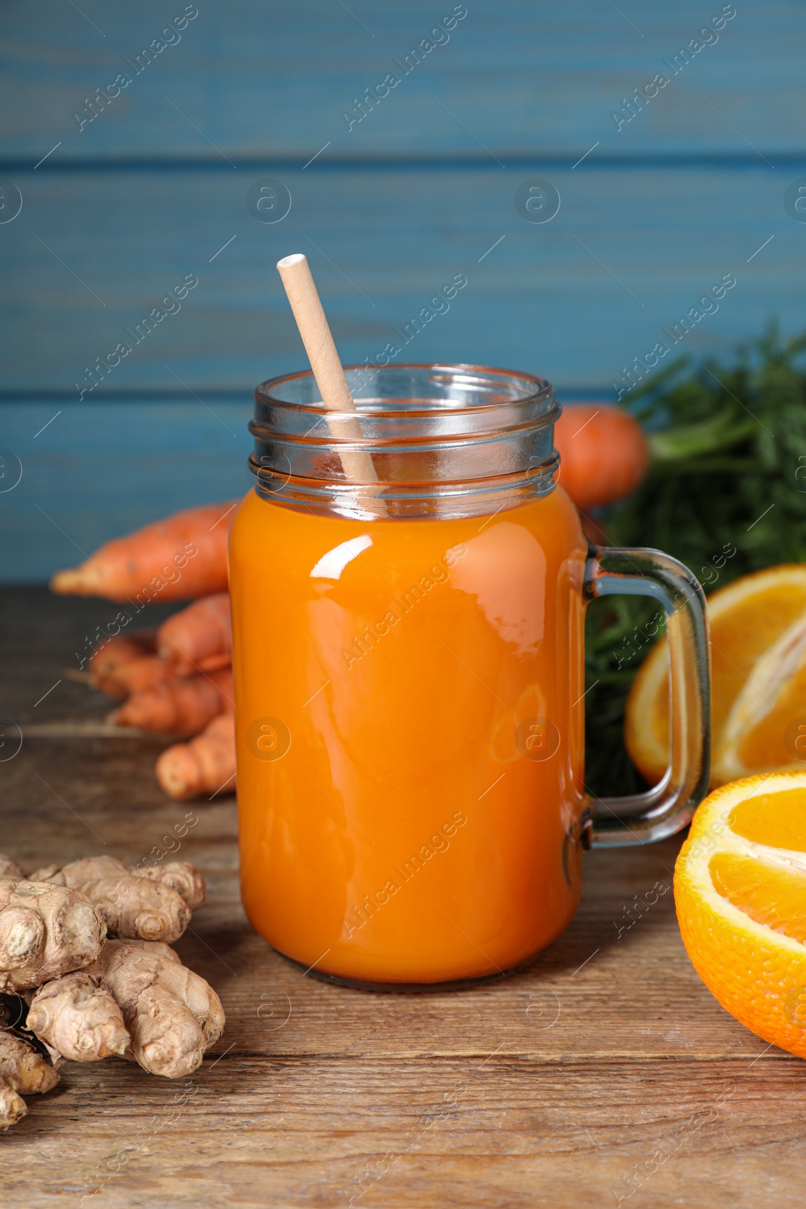 Photo of Freshly made carrot smoothie in mason jar and ingredients on wooden table