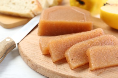 Photo of Tasty sweet quince paste, fresh fruits, bread and knife on white wooden table, closeup