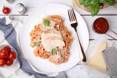 Delicious pasta with tomato sauce, chicken and parmesan cheese on white wooden table, flat lay